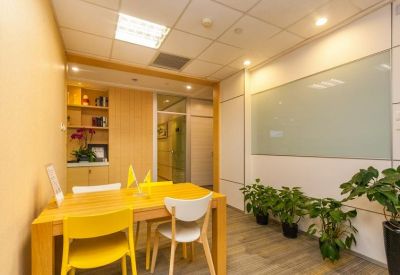 Small meeting room with a light wood table, yellow and white chairs, and a whiteboard.
