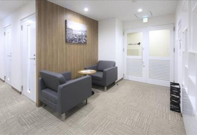 Inviting waiting area with grey armchairs, a side table, and wood-paneled wall.