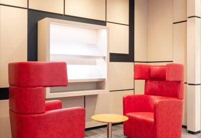 Private breakout area featuring two high-back red armchairs and a small round table.