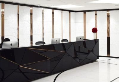 Sleek black geometric reception desk against a white paneled wall with copper accents.