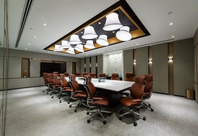 Formal boardroom featuring a long white table, leather chairs, and unique bell-shaped pendant lights.