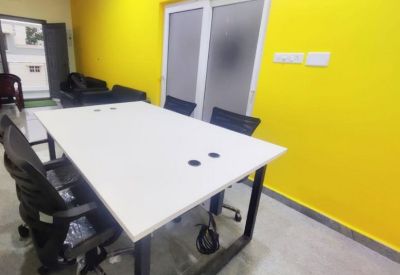 Meeting room with a white table, ergonomic black chairs, and a bright yellow feature wall.