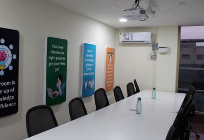 Long white conference table in a meeting room with motivational wall art and a ceiling projector.