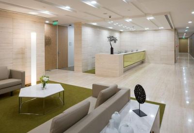 Bright reception area with a minimalist desk, polished floors, and a soft green rug area.