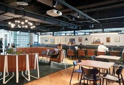 Expansive open-plan coworking space with various seating options and art-covered walls.