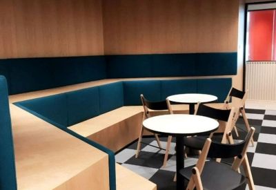 Built-in wooden bench seating with teal cushions and small round bistro tables.
