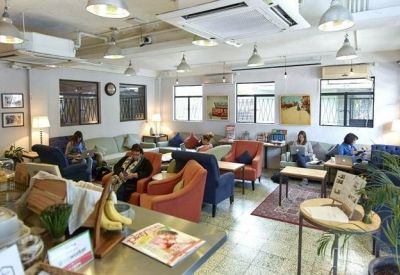 Bright communal lounge with colorful armchairs and several small coffee tables.
