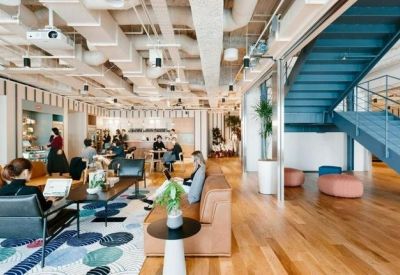 Large open-plan workspace featuring industrial ceilings, wooden floors, and a blue feature staircase.