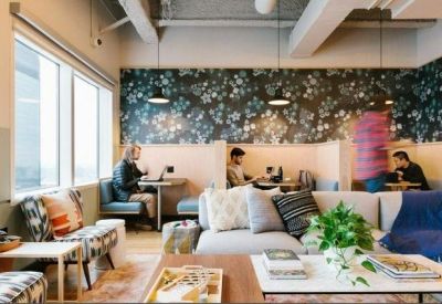 Cozy coworking area with floral wallpaper booths and comfortable grey sectional sofas.