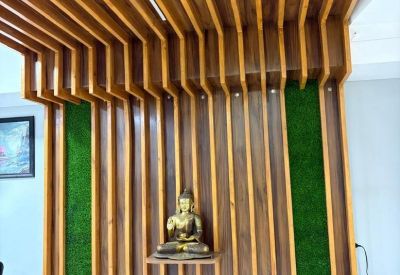 Reception area feature wall with vertical wood slats, artificial turf, and a golden Buddha statue.