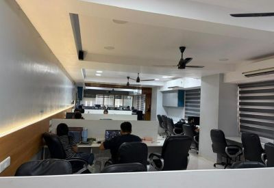 Workspace view from behind cubicle walls showing employees at computer stations.