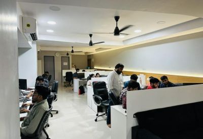 Spacious open-plan workspace with multiple ceiling fans and rows of white desks.