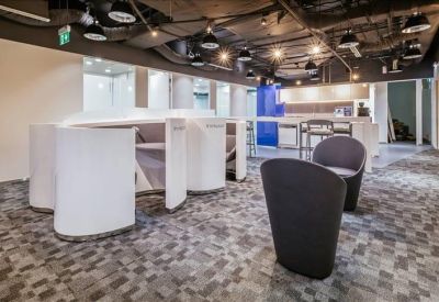 Brightly lit lobby with curved white workstations and modern grey armchairs.