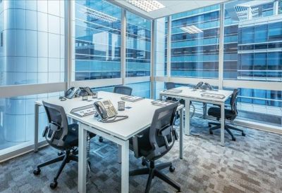 Modern coworking space with white desks and floor-to-ceiling windows showing city views.