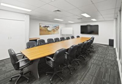 Professional boardroom with a long wooden table, black leather chairs, and wall-mounted screen.