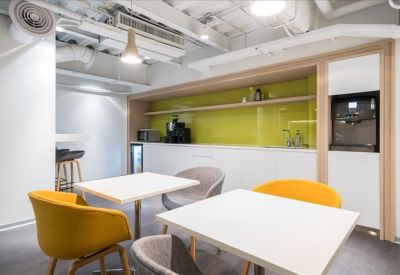 Modern communal kitchen and break area with yellow and grey seating.