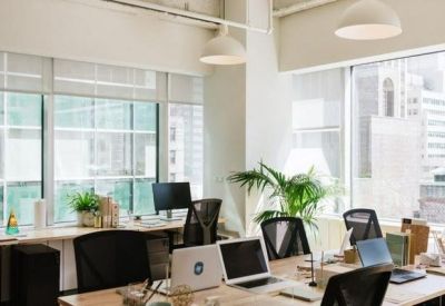 Bright open-plan office with white desks and black ergonomic chairs.