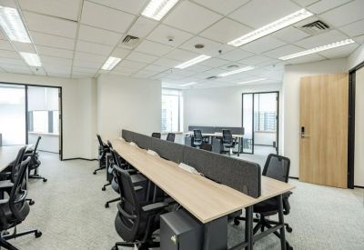 Open-plan office with multiple rows of workstations and light wood desks.