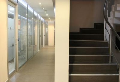 Well-lit corridor with glass partitions and stairs.