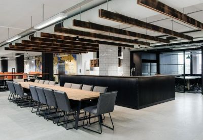 Spacious communal dining and breakout area with a long wooden table and dark overhead beams.