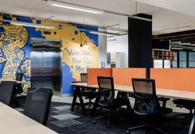Office workspace with wooden desks, orange dividers, and a vibrant blue and yellow wall mural.