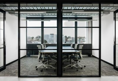 Modern conference room with a long table behind a black-framed glass partition.