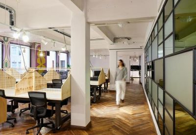 Open-plan workspace with timber-partitioned desks and parquet flooring.