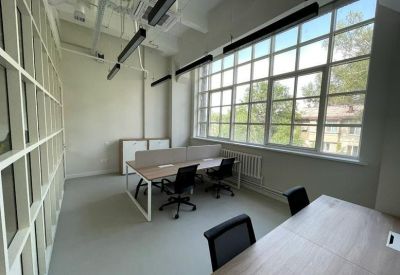 Bright office suite with large windows and multiple workstations.