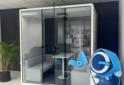 A private, glass-walled meeting pod with a small table and seating inside a modern office.