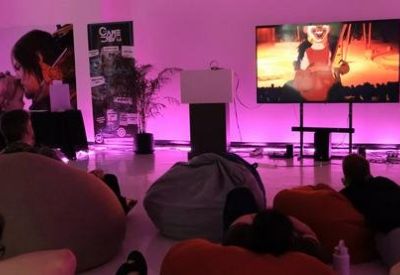 Breakout area with beanbags and a large screen illuminated by purple ambient lighting.