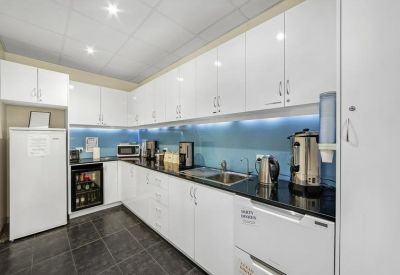 Sleek modern kitchen with white cabinetry, black countertops, and under-cabinet lighting.