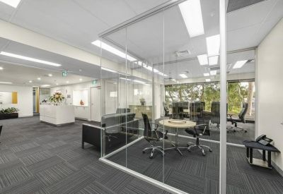 Spacious reception area with a glass-walled meeting room and a white front desk.