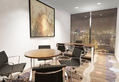 Small meeting room with a round wooden table and dark leather chairs overlooking the city.