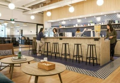 Lounge area with coffee bar, high stools, and comfortable armchairs on a patterned floor.