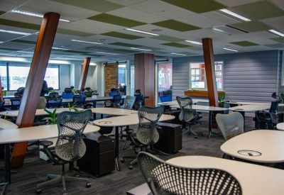 Large open-plan office with ergonomic chairs and wooden support beams.
