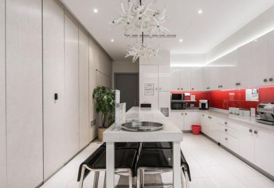 Modern white communal kitchen with a red backsplash and breakfast bar.