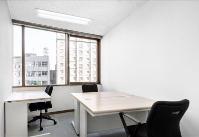 Bright corner office with two desks and large windows overlooking the city.