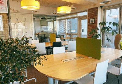 Coworking area with long wooden tables, colorful chairs, and warm pendant lighting.