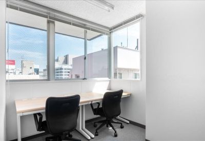 Bright corner office with two desks and large windows overlooking the city.