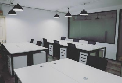 Spacious communal workspace with white desks and modern black pendant lighting.