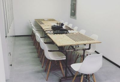 Minimalist meeting room featuring a long wooden table with white chairs.