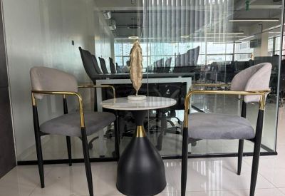 Chic breakout area featuring a small round table, velvet armchairs, and a decorative gold sculpture.