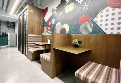 Communal breakout area with wooden booths, striped seating, and a colorful abstract mural.
