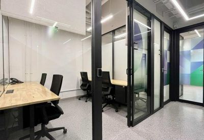 Bright internal office suite featuring glass partitions and natural wood workspaces.