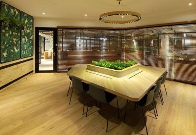 Large wooden meeting table with a central planter box and leaf-patterned wall art.