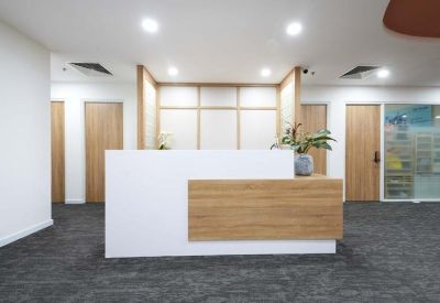 Modern reception desk with white and wood finishes under bright recessed lighting.