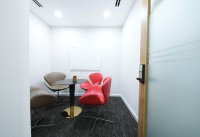 Small meeting room with red and grey chairs around a circular table.