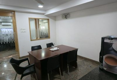 Small meeting room with a wooden table and black chairs.