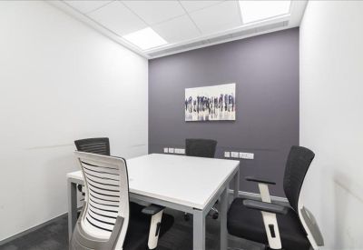 Small meeting room with four chairs, a white table, and minimalist wall art.