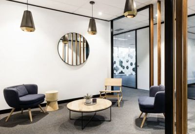 Casual break area with modern armchairs, a round coffee table, and geometric glass partitions.